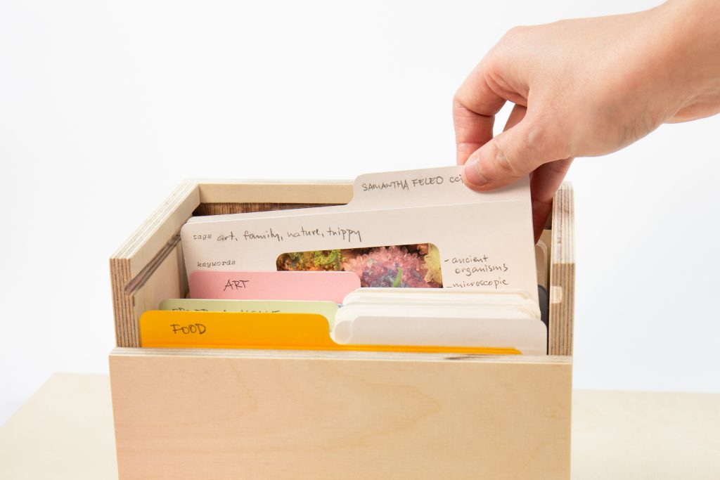 A hand placing catalogued Memory Cards into a wooden archive box